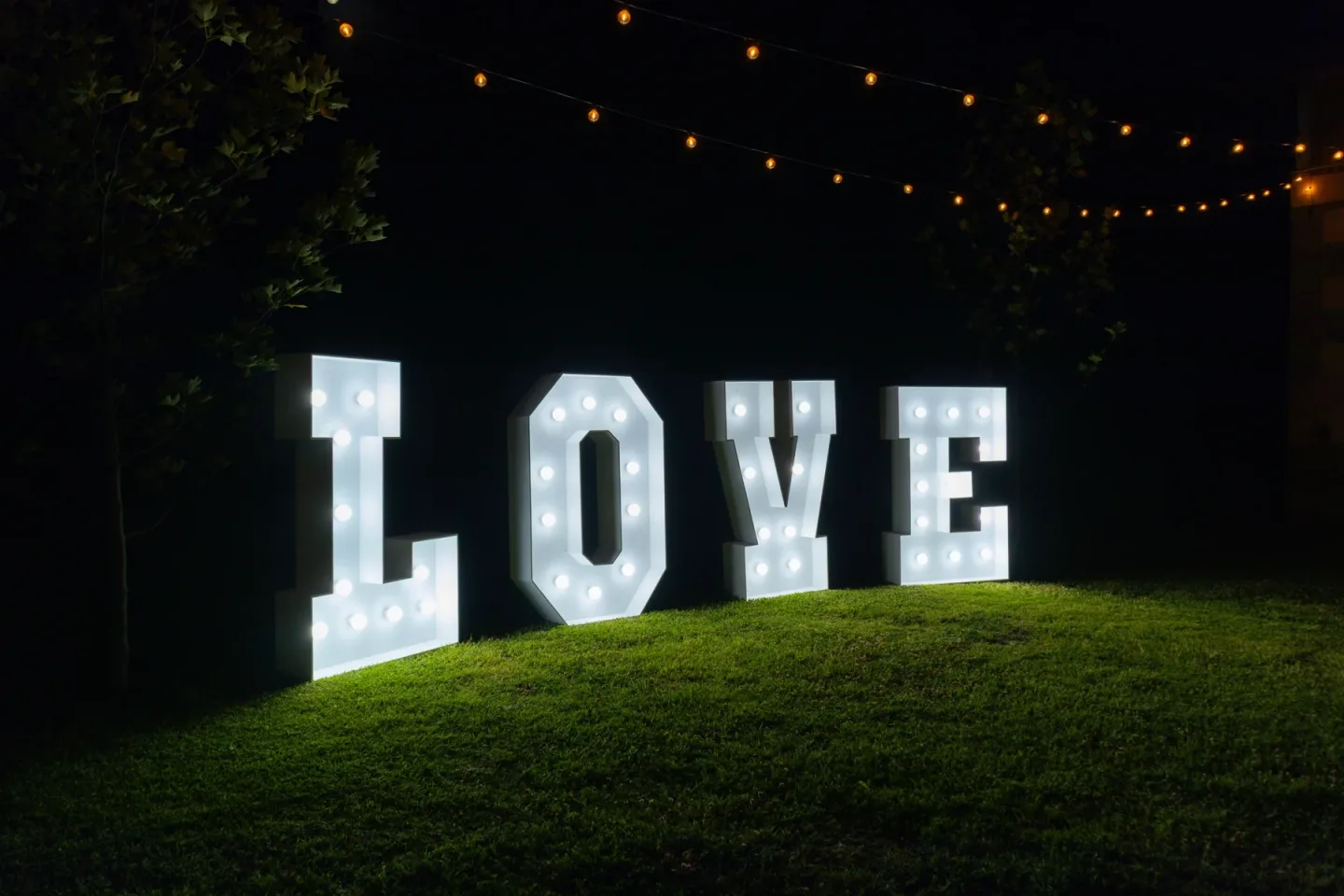 Letras LOVE Vintage iluminadas en un jardín de noche